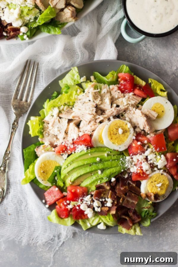 A close-up of the Turkey Cobb Salad showcasing the vibrant colors and fresh textures of the ingredients. Neatly arranged rows feature succulent turkey pieces, crisp bacon bits, and the creamy richness of avocado slices.