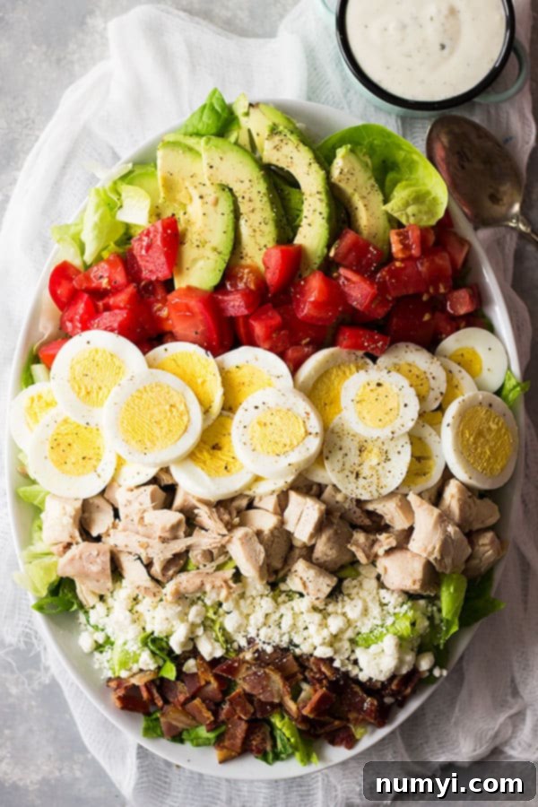 Detailed shot of the Turkey Cobb Salad, emphasizing the hearty components like chopped hard-boiled eggs, juicy diced tomatoes, and crumbled cheese, adding depth and flavor to the healthy greens base.