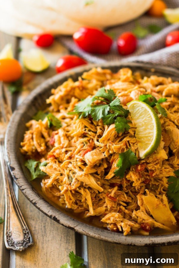 crockpot mexican chicken in a bowl with lime wedges