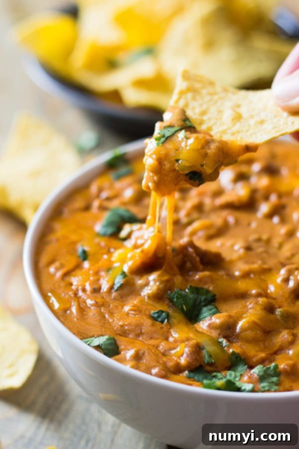 A serving spoon lifting creamy chili cheese dip from a crock pot, showcasing its perfect texture