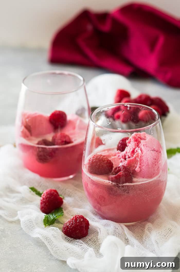 Two glasses with raspberry sherbet and fresh raspberries, prepared for pink champagne to be poured, on a elegant background.