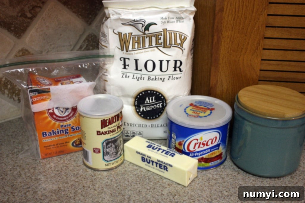 Easy Homemade Tender Soft Flaky Biscuits 3 Various cold biscuit ingredients on a counter top, including flour, baking powder, baking soda, salt, butter, and shortening.