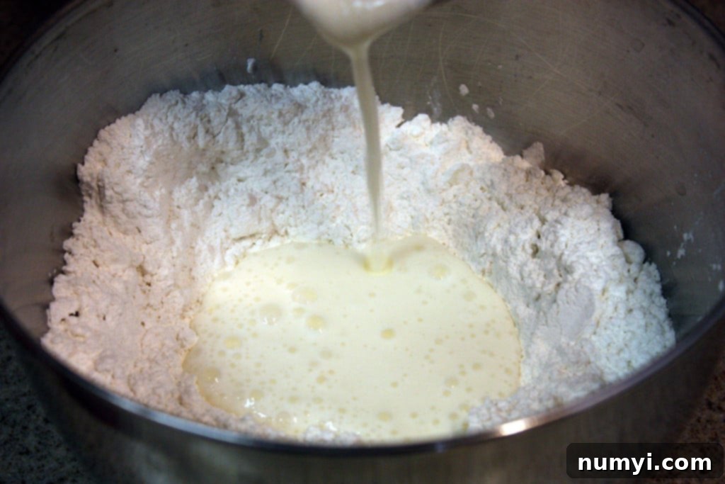 Easy Homemade Tender Soft Flaky Biscuits 6 Cold buttermilk being poured into a well in the center of the flour and fat mixture.