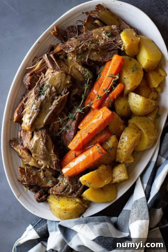 Melt-in-Your-Mouth Pot Roast 4 Top down view of roast, carrots, and potatoes on a serving plate.