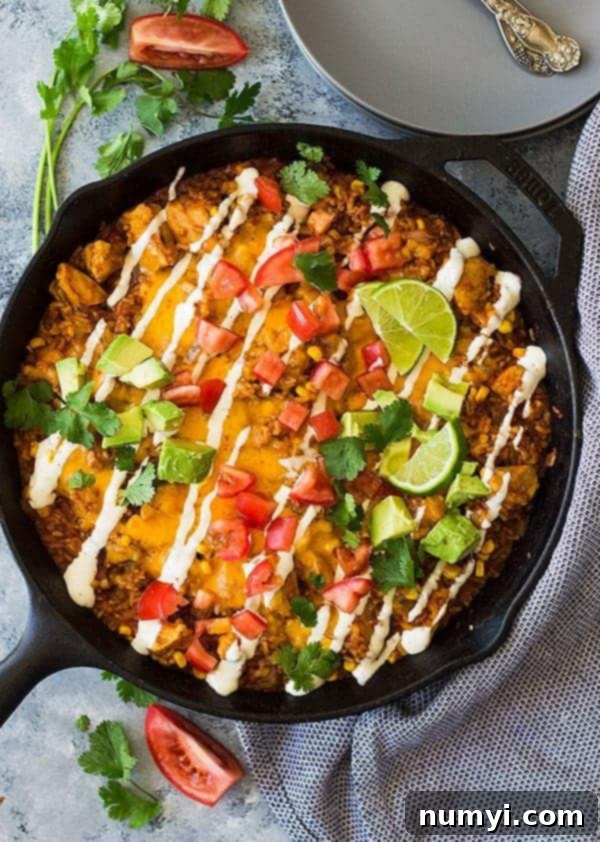 Delicious One Pot Chicken BBQ Rice 2 overhead: a skillet full of BBQ rice with cheese, avocado, and tomatoes on top