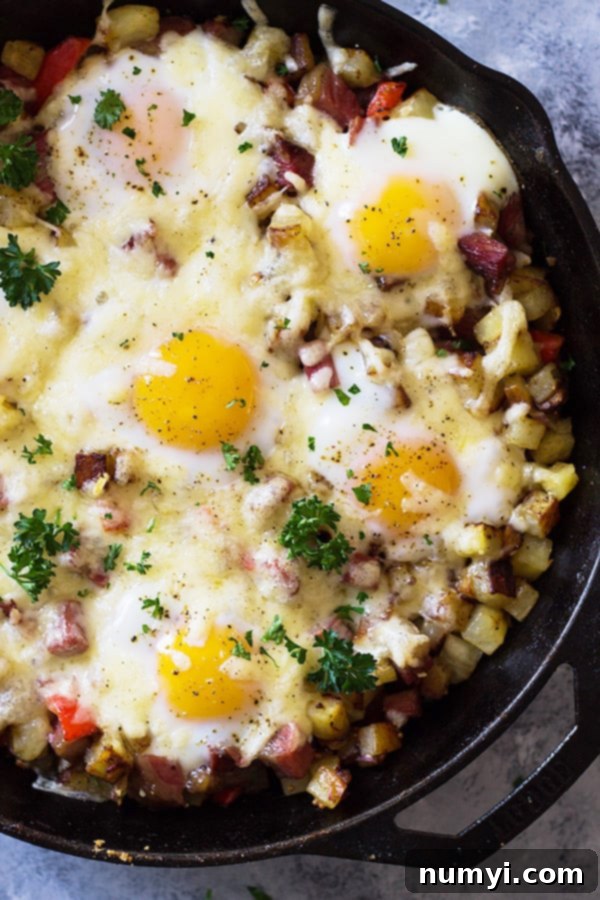 Close-up of golden Cheesy Corned Beef Hash with perfectly baked eggs, ready to be served from a skillet