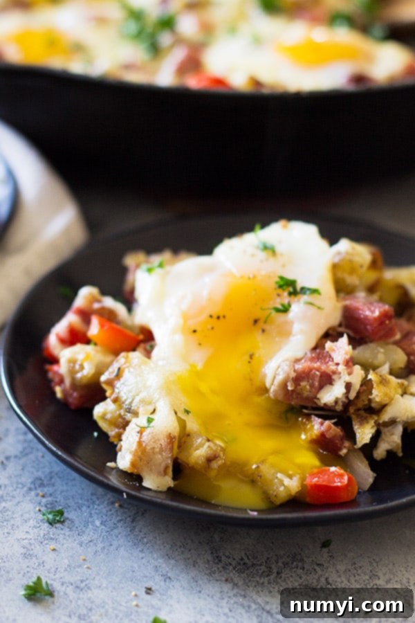 Scoop of Cheesy Corned Beef Hash on a plate, highlighting the rich texture and melted cheese