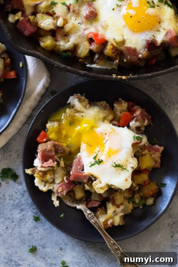 Overhead shot of Cheesy Corned Beef Hash with several baked eggs nestled in the mixture, yolks still runny