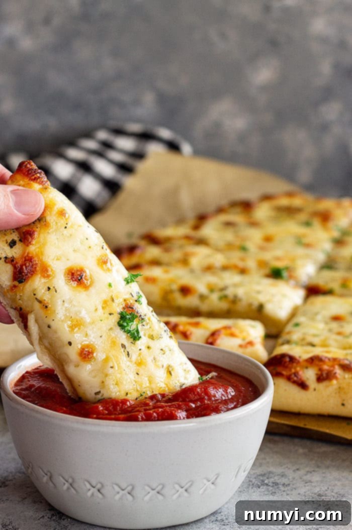 Bread stick being dunked into sauce.