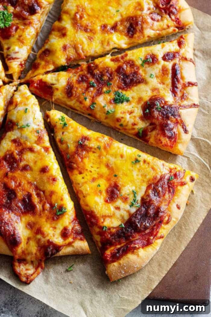Perfectly Homemade Cheese Pizza 2 overhead: cooked and sliced cheese pizza on parchment paper