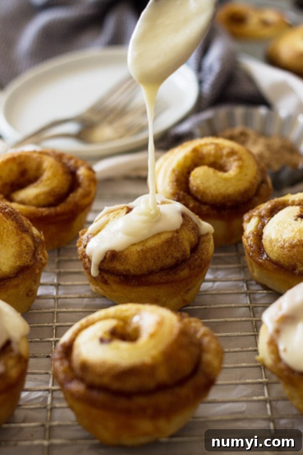 Close-up of baked cinnamon roll muffins showing the swirl, before icing, cooling in a muffin tin.