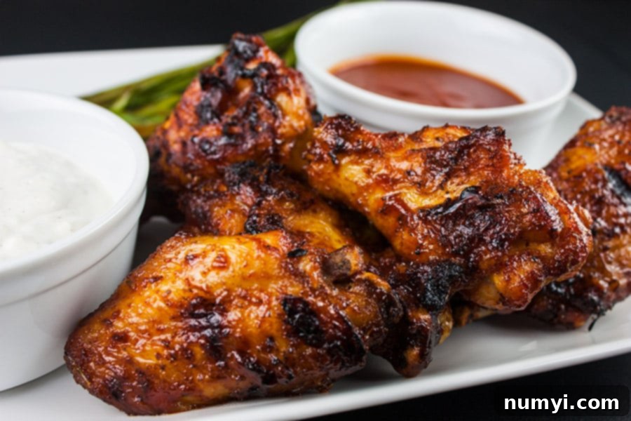 Cajun Smoked Wings with two sauces on a white plate, showcasing crispy skin and rich color.