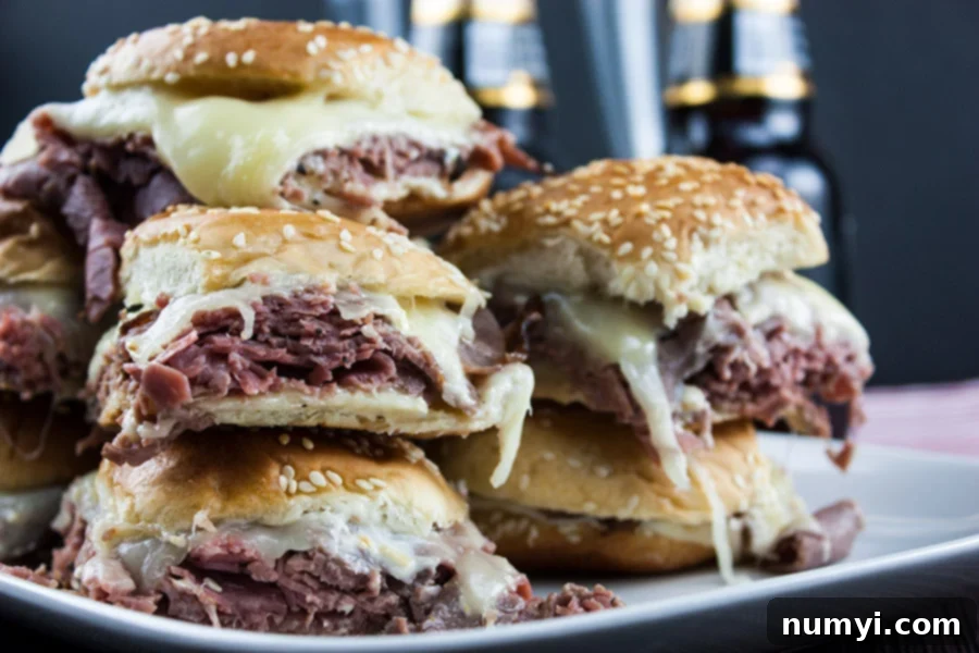 Smoky Roast Beef Sliders with Zingy Horseradish 2 Roast beef sliders stacked on white plate beer bottles in background.