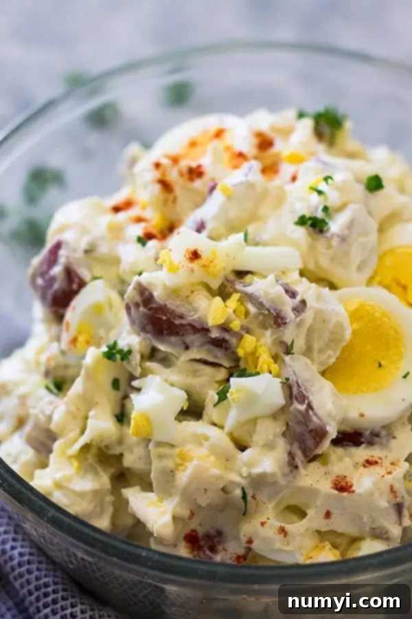 Grandma's Potato Salad 3 Close-up of creamy potato salad in a clear glass bowl, showcasing the tender potatoes and egg pieces, ready to serve.
