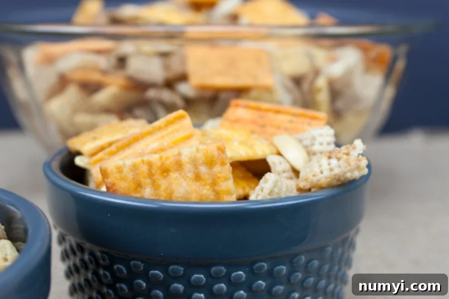 Addictive Spicy Cheddar Snack Mix in a blue serving bowl, perfect for parties and gatherings.