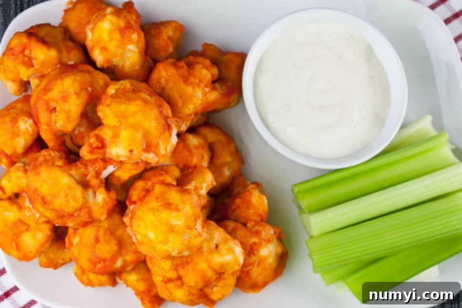 Crispy Baked Buffalo Cauliflower Bites served on a white platter with fresh celery sticks.