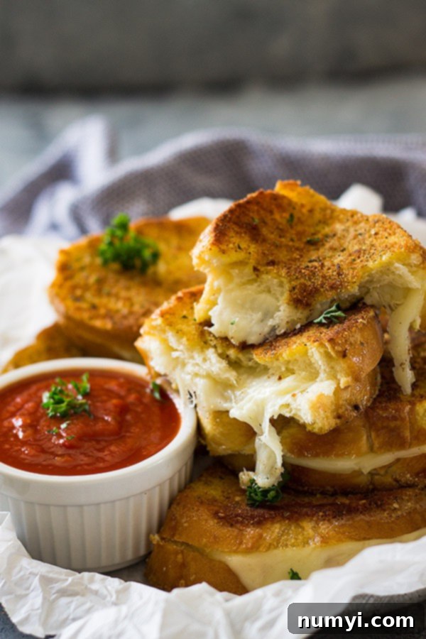 Gourmet Italian Grilled Cheese 3 Perfectly sliced Italian grilled cheese sandwiches, showing off their golden crust and gooey Provolone filling, arranged artfully next to a small white bowl of savory pizza sauce.