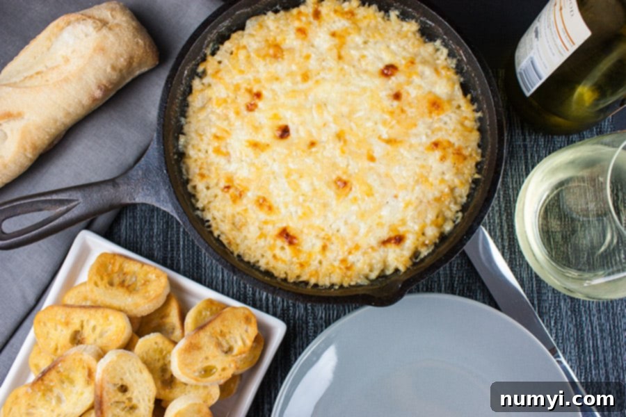 Baked Vidalia Onion Dip in a cast iron skillet with toasted baguette slices on a white platter, perfect for serving.