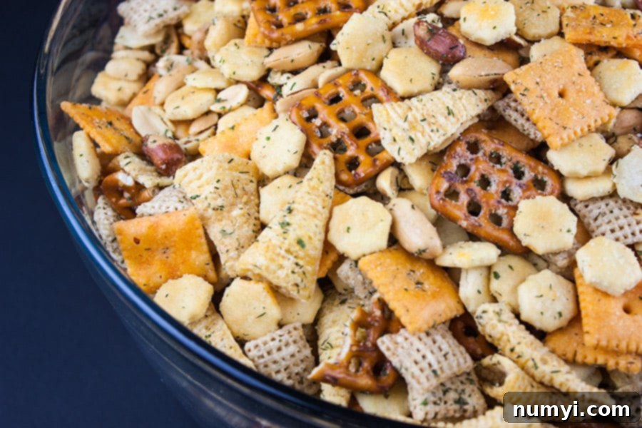 A vibrant blue serving bowl overflowing with golden brown Ranch Party Mix, featuring a delicious assortment of crackers and nuts, perfectly seasoned and ready for snacking.