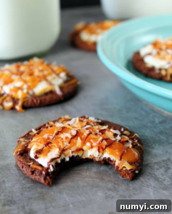 Decadent Chocolate Samoa Cookies 3 A close-up of a single Chocolate Samoa Cookie with caramel and coconut topping, showing a bite taken out, emphasizing its chewy texture and delicious layers.