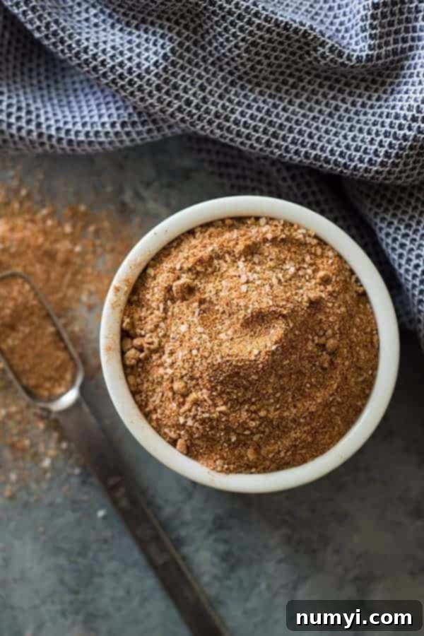 overhead: garlic, cayenne pepper, paprika, brown sugar, and garlic powder homemade pork rub in white ramekin with spoon