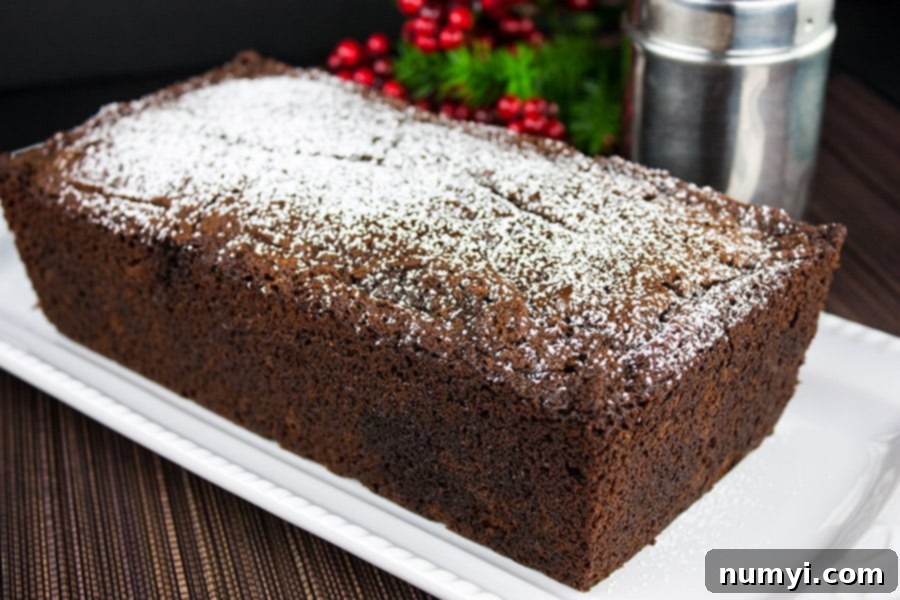Spicy Gingerbread Loaf on a white platter garnished with powdered sugar, ready to be served.