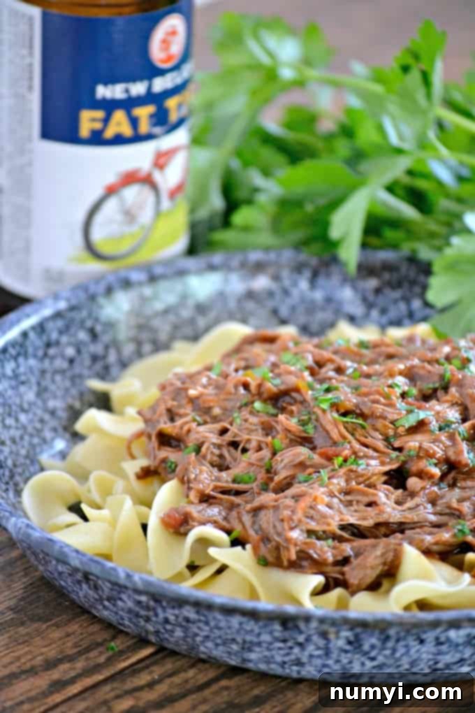 Hearty Slow Cooker Chili Beer Pot Roast, fork-tender and surrounded by vegetables.