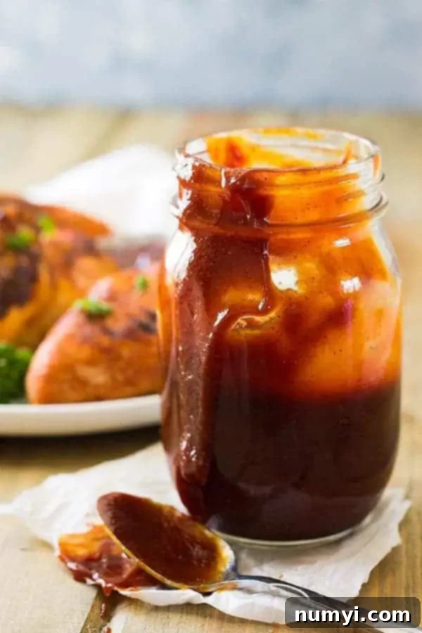 side view: Kansas City BBQ sauce in mason jar with spoon next to it
