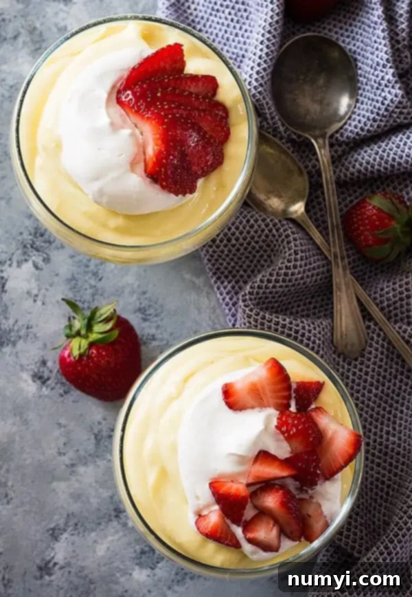 overhead: 2 small bowls of vanilla pudding with whipped cream and fresh strawberries on top