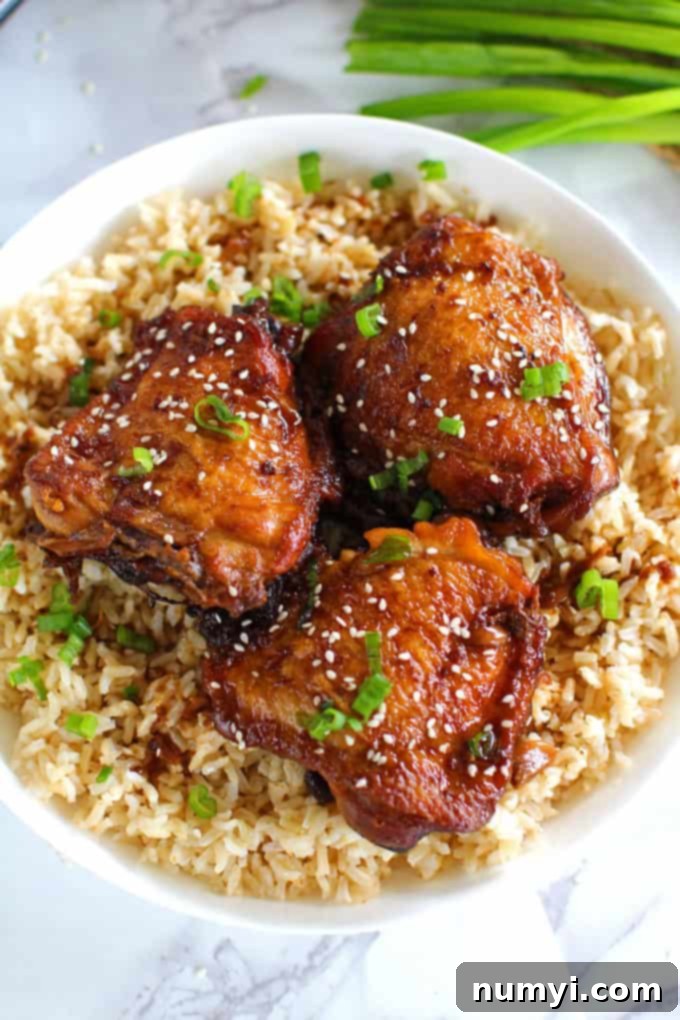 Slow Cooker Garlic Sesame Chicken, beautifully plated with white rice and steamed broccoli, garnished with green onions.