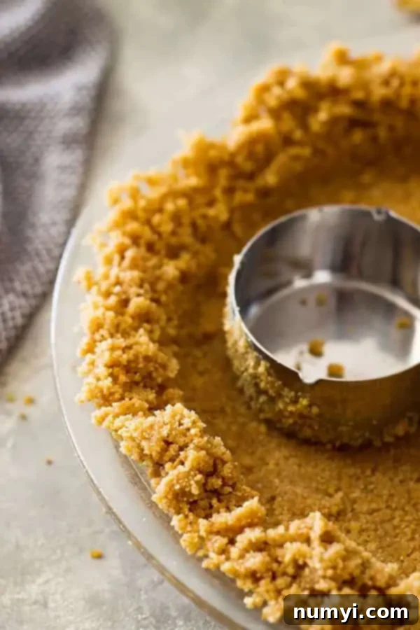 Perfect Homemade Graham Cracker Crust 2 closeup: pressing my graham cracker pie crust recipe into pie pan with measuring cup