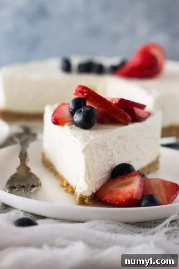 Creamy No-Bake Vanilla Cheesecake 4 Front view of a slice of whipped cheesecake topped with fresh berries, showing its light texture.