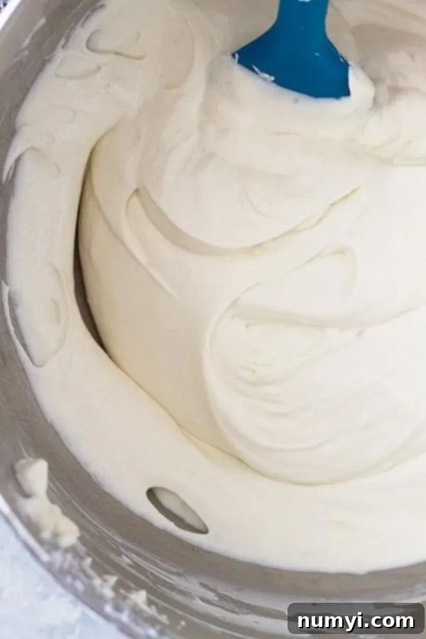 Creamy No-Bake Vanilla Cheesecake 5 Overhead view of whipped cream being folded into cream cheese with a spatula.