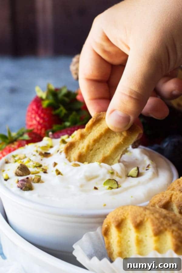 A bowl of creamy, white marshmallow fruit dip surrounded by fresh strawberries and blueberries, ready for dipping.