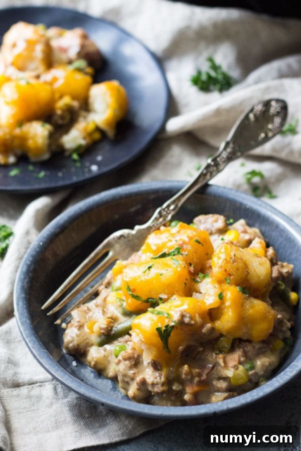Bowl of Bacon Cheeseburger Tater Tot Casserole with fork and second bowl in background. 