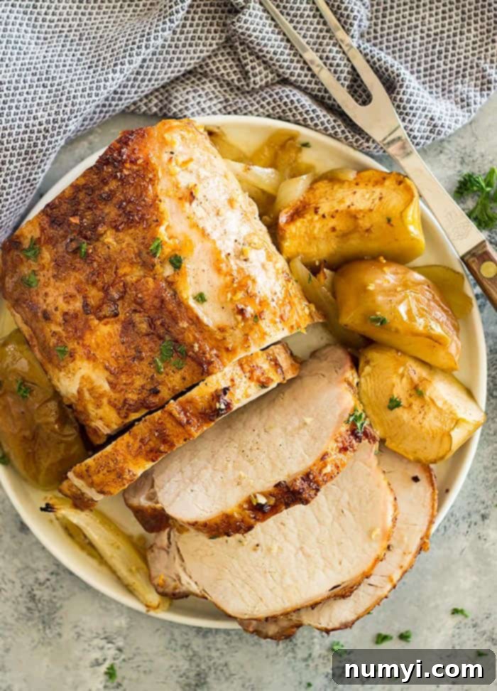Succulent maple roasted pork loin with tender apples and caramelized onions on a platter, ready to be served.