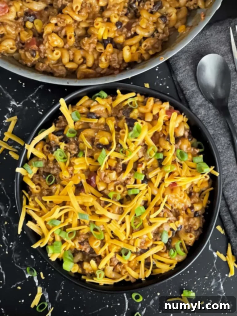 A serving of the delicious one-pot taco pasta skillet in a dark bowl, ready to be enjoyed.