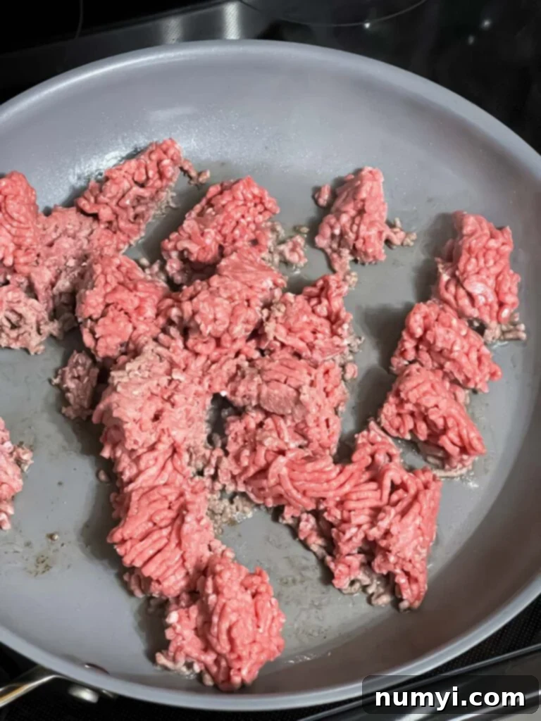 Ground beef browning in a large skillet over medium-high heat.