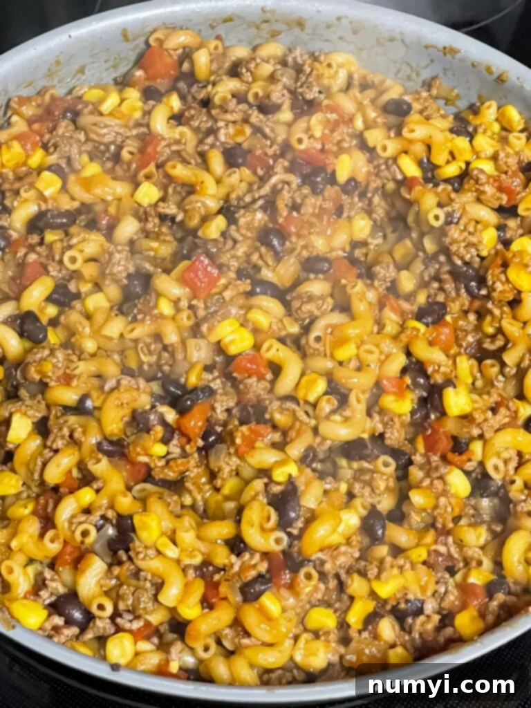 The one-pot taco pasta skillet simmering on the stove, with pasta absorbing the savory sauce.