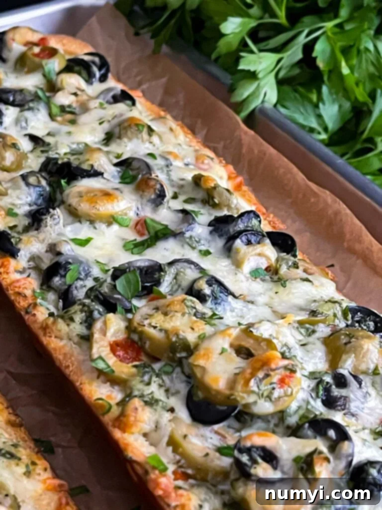 Olive cheese bread on a parchment paper lined baking sheet, golden brown and bubbly.