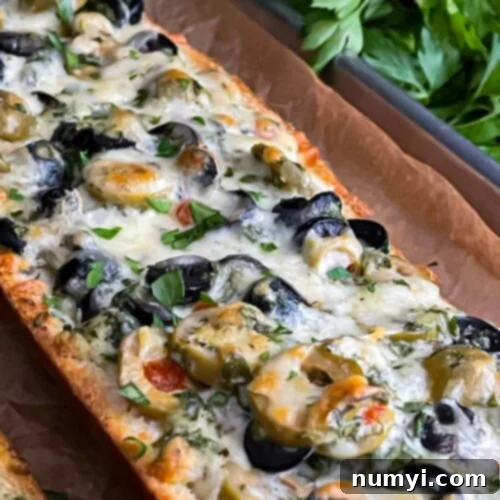 Olive cheese bread on a parchment paper lined baking sheet, golden and bubbly.