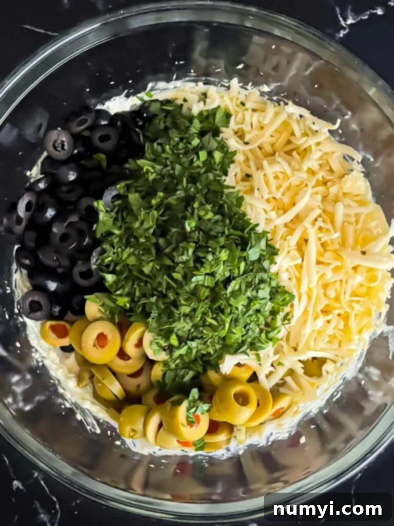 Olive cheese bread ingredients in a glass mixing bowl, before being mixed.
