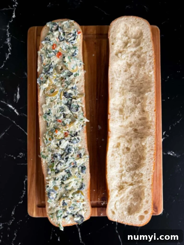 Olive cheese mixture spread inside half of the bread loaf, ready for baking.