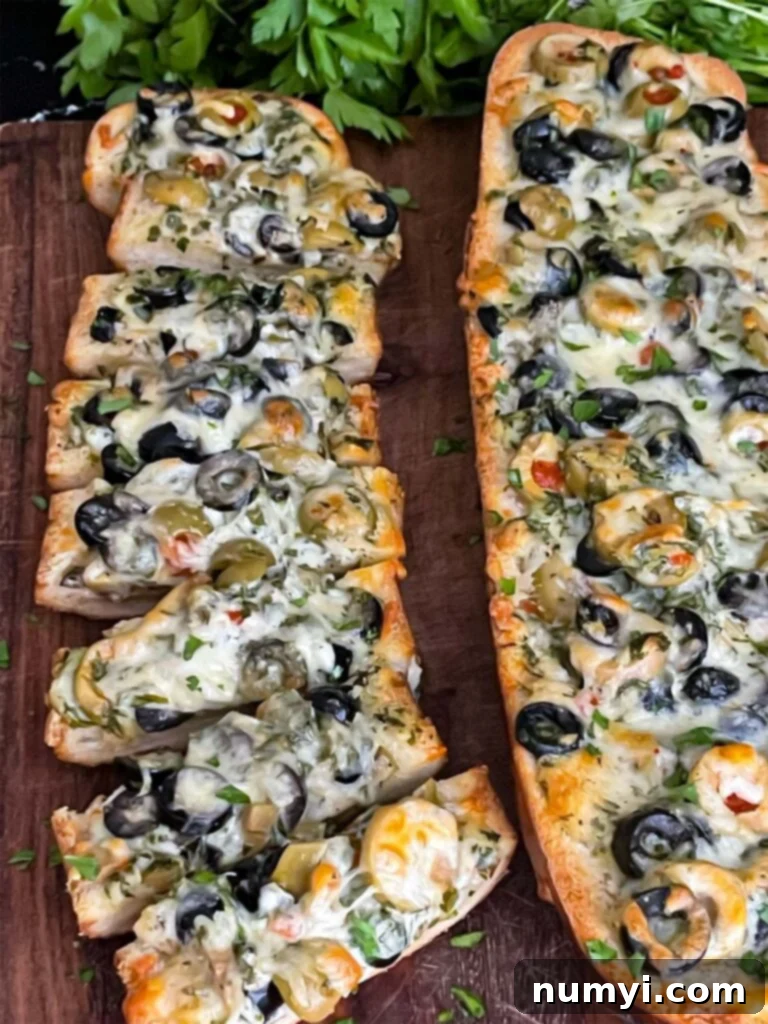 Sliced olive cheese bread on a wooden cutting board, ready to serve.
