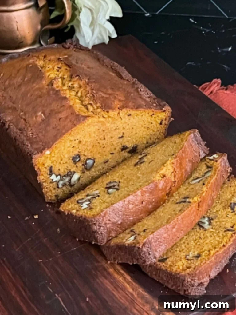 Sweet potato bread sliced on a wooden board. A perfect slice reveals the moist interior and speckles of sweet potato.