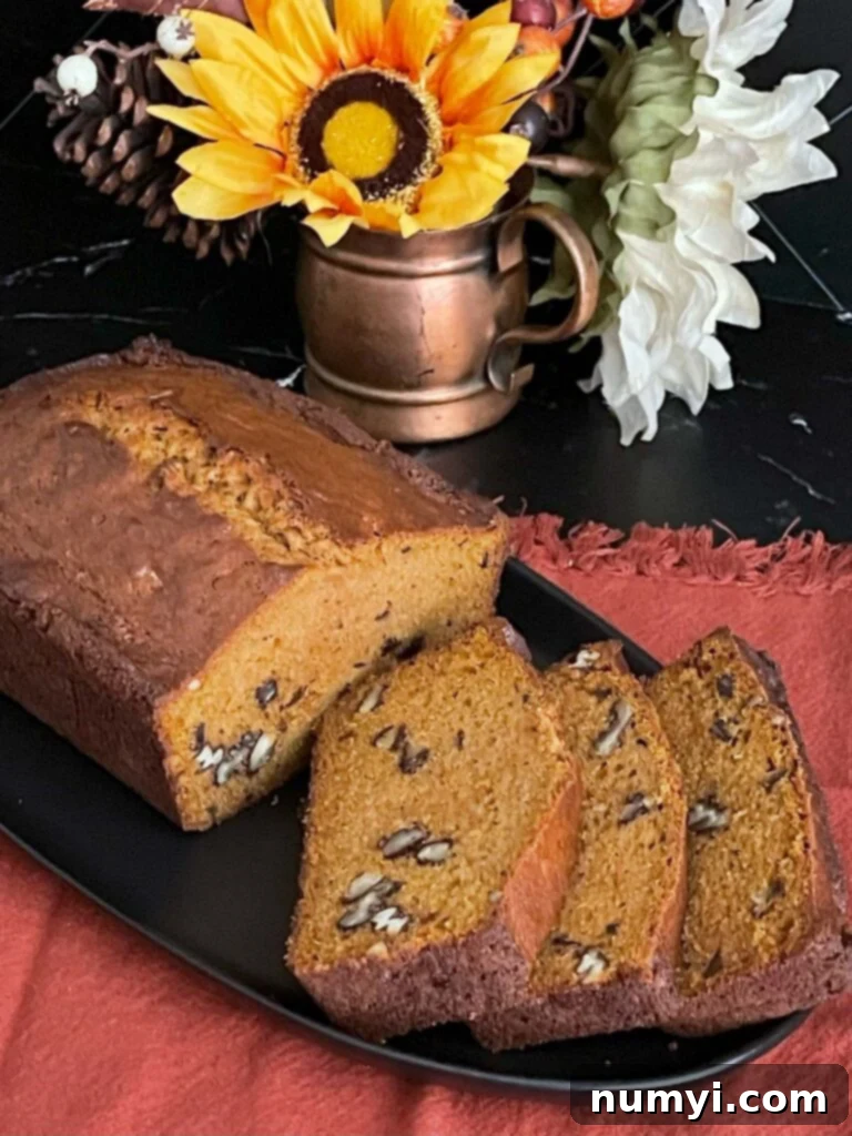 Freshly baked and sliced sweet potato bread on a dark platter, showing its golden crust and moist interior.