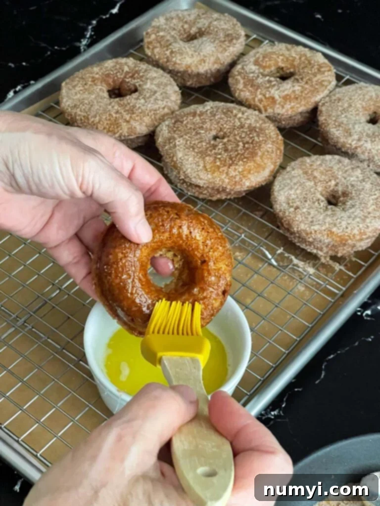 Spiced Apple Cider Baked Doughnuts 8 Melted butter being brushed over a baked apple cider donut.