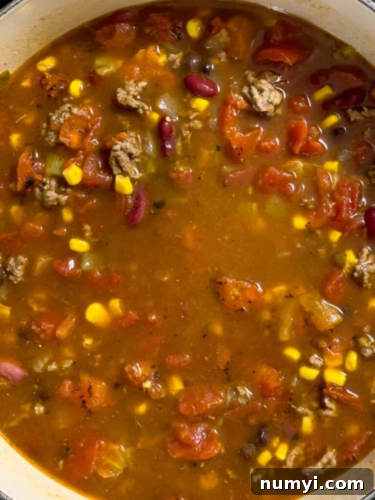 Taco soup gently simmering in a dutch oven on the stove.