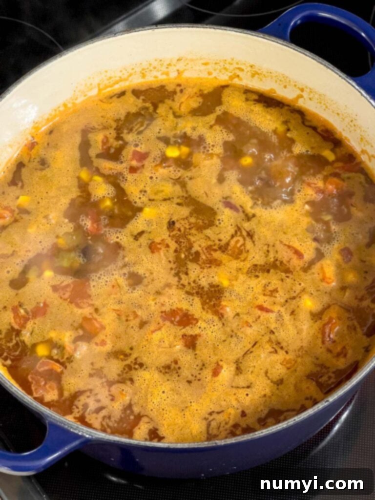 Taco soup bubbling gently as it cooks in a dutch oven.