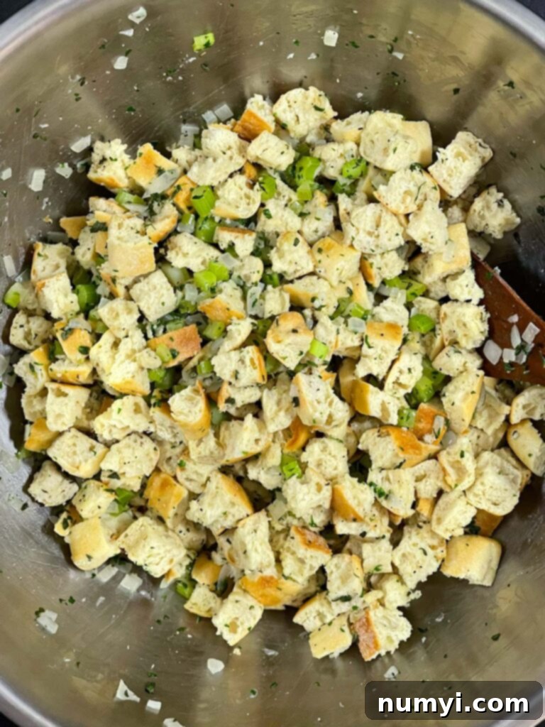 The stuffing mixture, a harmonious blend of bread, vegetables, and fragrant herbs, fully combined in a bowl.